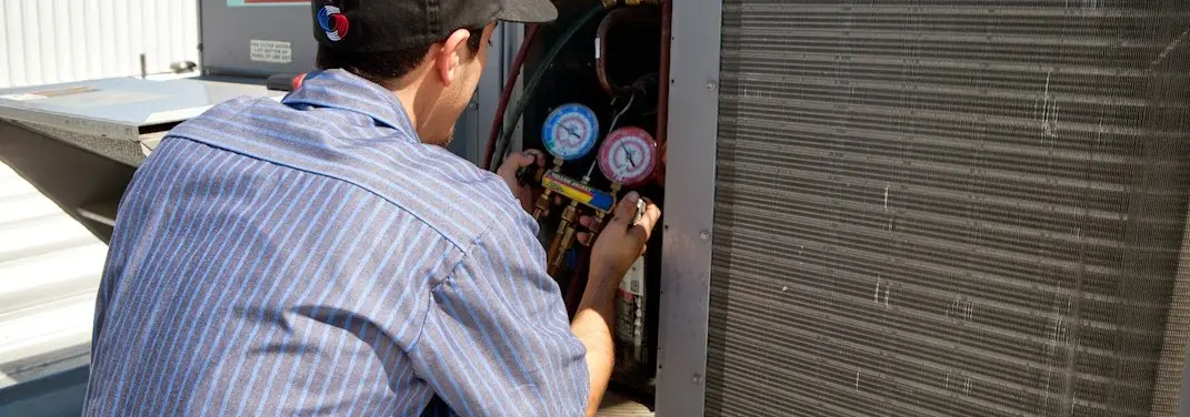HVAC technician servicing a condenser unit in Dayton